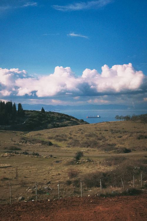 Free Beautiful countryside landscape with a ship on the horizon under a bright blue sky. Stock Photo