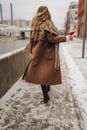 Unrecognizable Blond Woman in Brown Coat and Glass of Red Wine