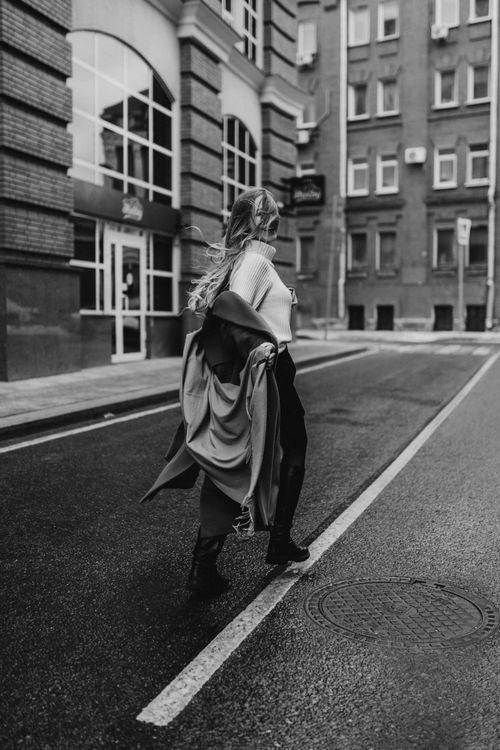 Free Black and white photo of a stylish woman walking in an urban street setting. Stock Photo