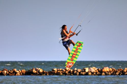 Free A kitesurfer performs an aerial trick over the ocean near a rocky seashore. Stock Photo