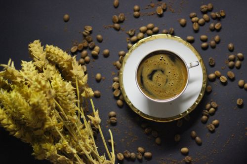Free Stylish flatlay featuring a coffee cup, beans, and dried wheat on a dark surface. Stock Photo