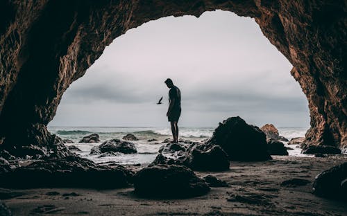 無料 海岸近くの岩の上に立っている男の写真 写真素材