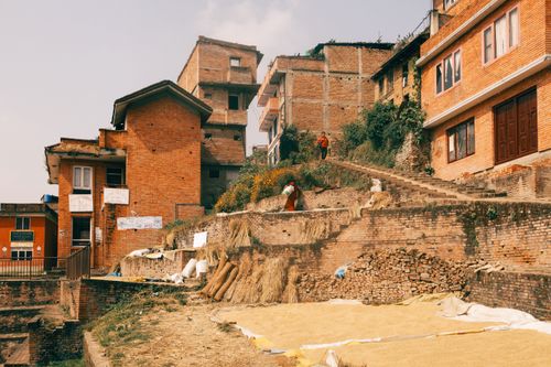 Free Rural scene with brick architecture and rice drying under the sun in a hillside neighborhood. Stock Photo
