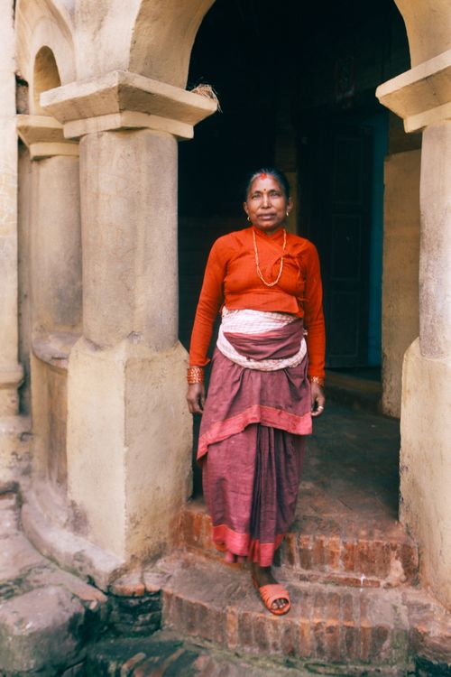 Free Elderly woman standing in traditional attire by ancient stone pillars, exuding a serene expression. Stock Photo