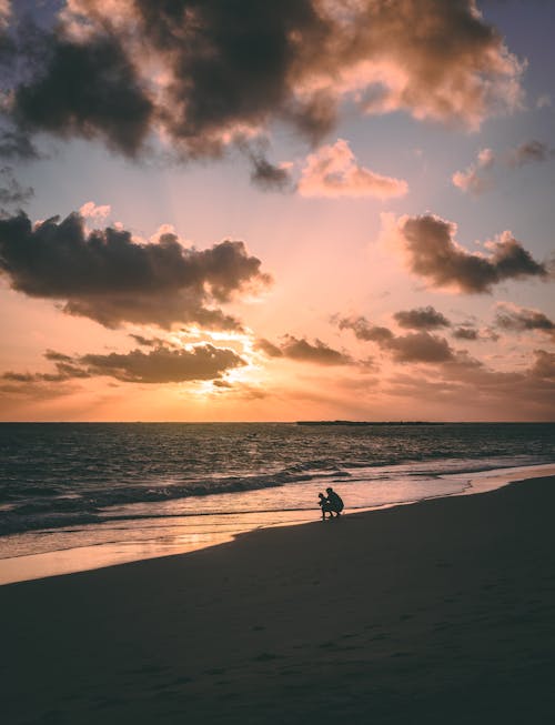 Kostenlos Schattenbild Der Zwei Person An Der Küste Während Des Sonnenuntergangs Stock-Foto