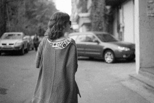 Black and white photo of a woman walking through a city street, embodying urban lifestyle.