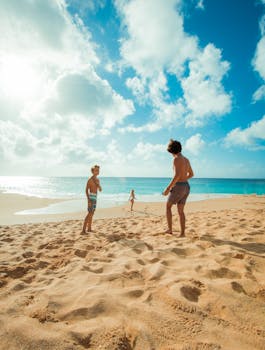 Three children enjoy a sunny day playing on Waialua Beach, Hawaii, with clear skies and blue ocean waters.