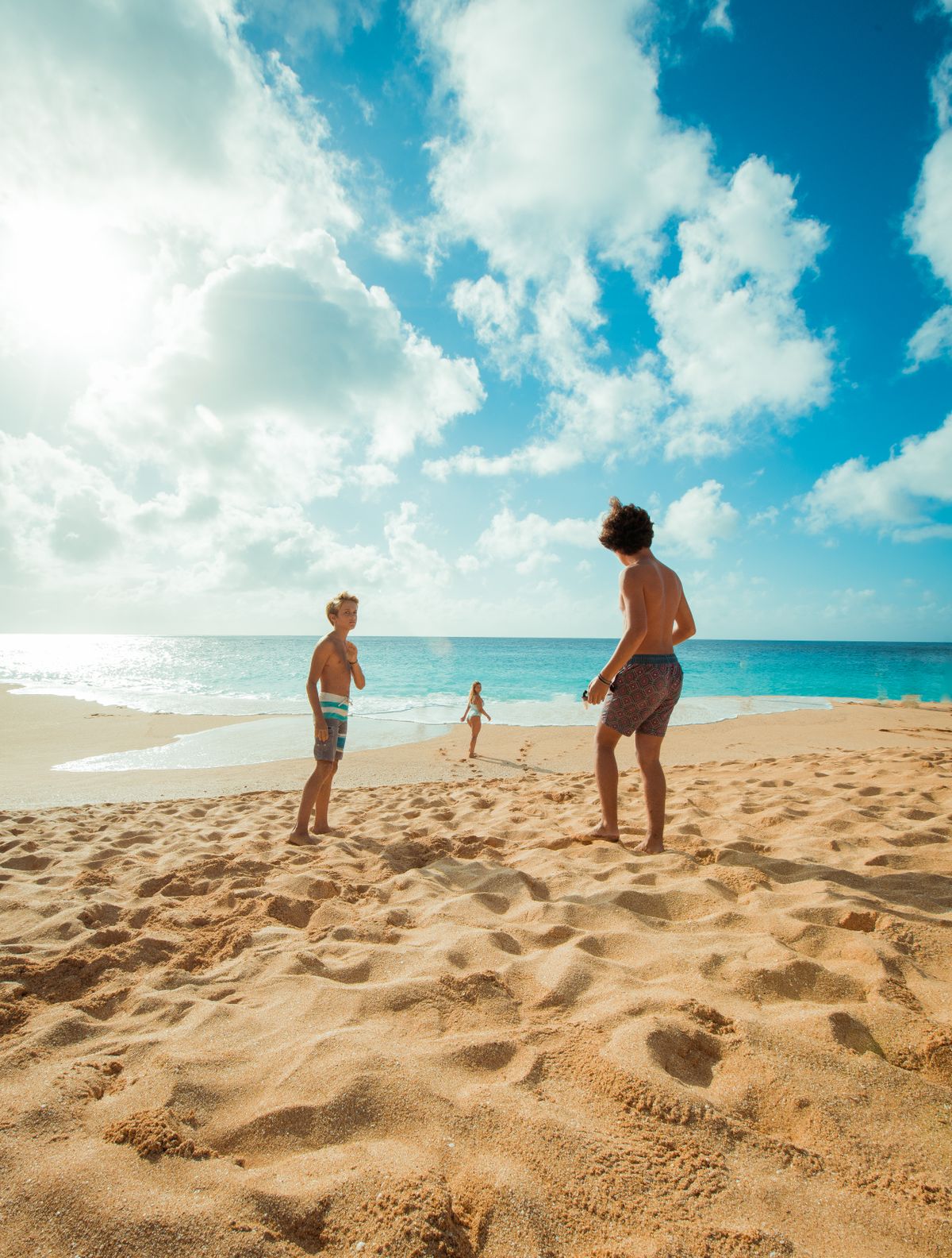 Children enjoy a sunny day playing on a Hawaiian beach with clear skies and blue ocean