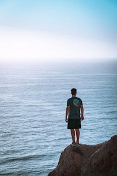 Man Standing on Cliff Near Sea