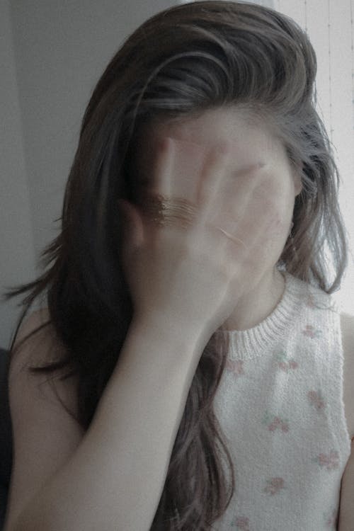 A Woman in White Tank Top Covering Her Face