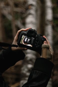 A close-up shot of a DSLR camera display being captured outdoors, highlighting the photographer's hands.