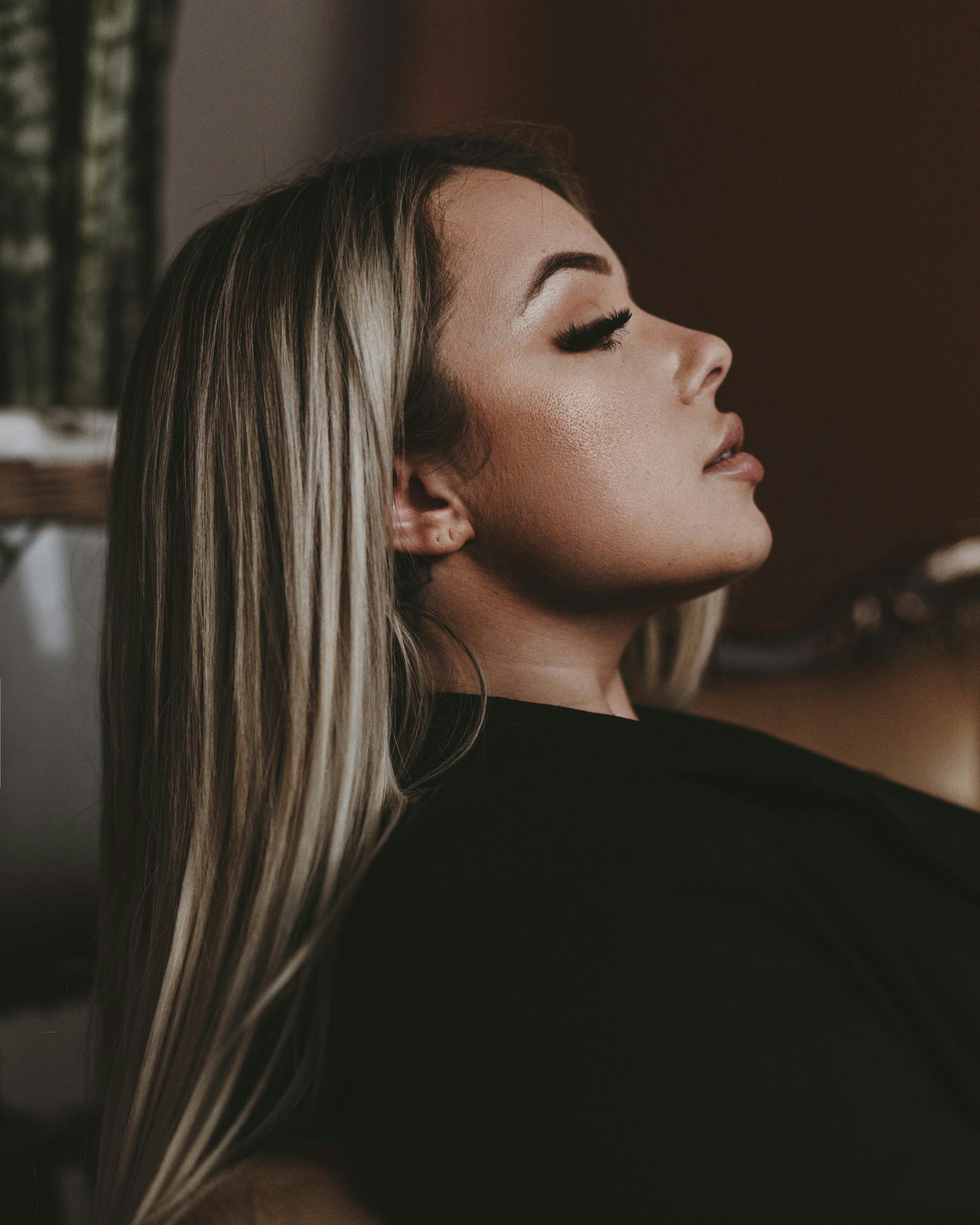 Sophisticated side profile portrait of a woman with long hair and closed eyes.