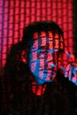 Red Inscriptions from Projector Displayed on Face of Young Man
