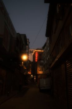 Dimly lit urban alley at night featuring a prominent neon hotel sign, evoking a mysterious ambiance.