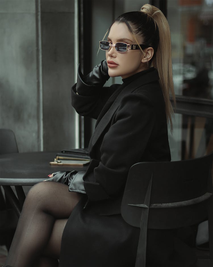 Woman In Sunglasses And High Ponytail Sitting By Table