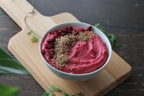 Free Colorful beetroot hummus garnished with sesame seeds in a white bowl on a wooden board. Stock Photo