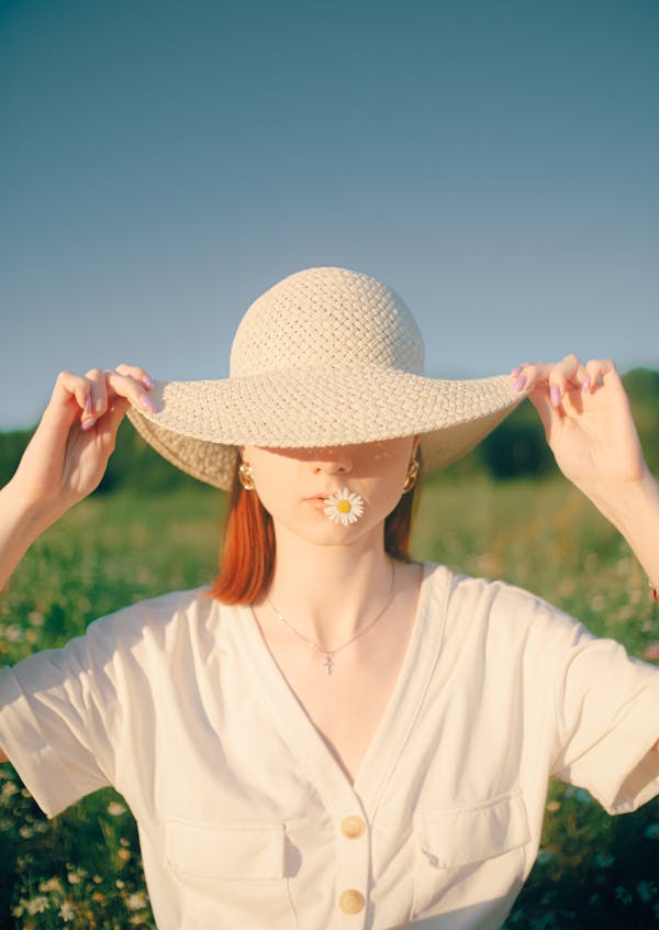 Redhead Woman Covering Eyes with Straw Hat Brim