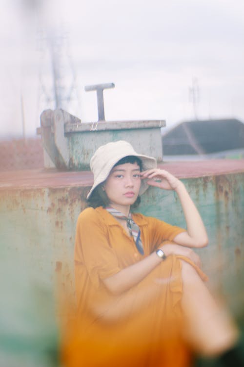 Partially Blurred Photo of Woman in Orange Dress Sitting