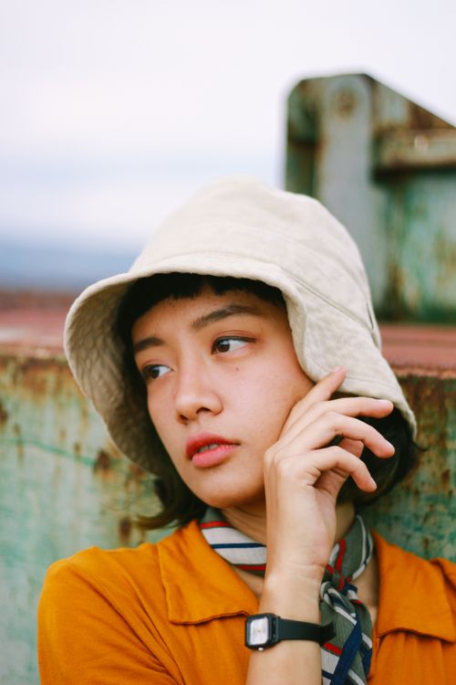 Free Portrait of a woman in a yellow dress, wearing a hat, looking thoughtfully aside. Stock Photo