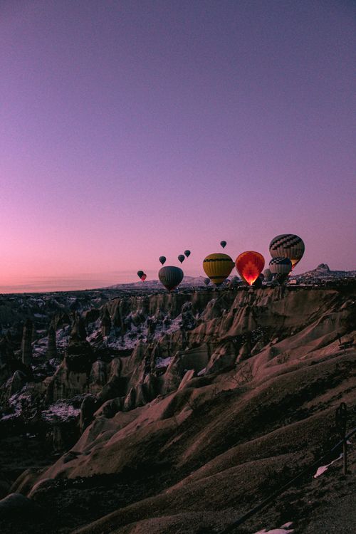 Free Scenic view of colorful hot air balloons floating over Cappadocia's unique landscape during sunset. Stock Photo