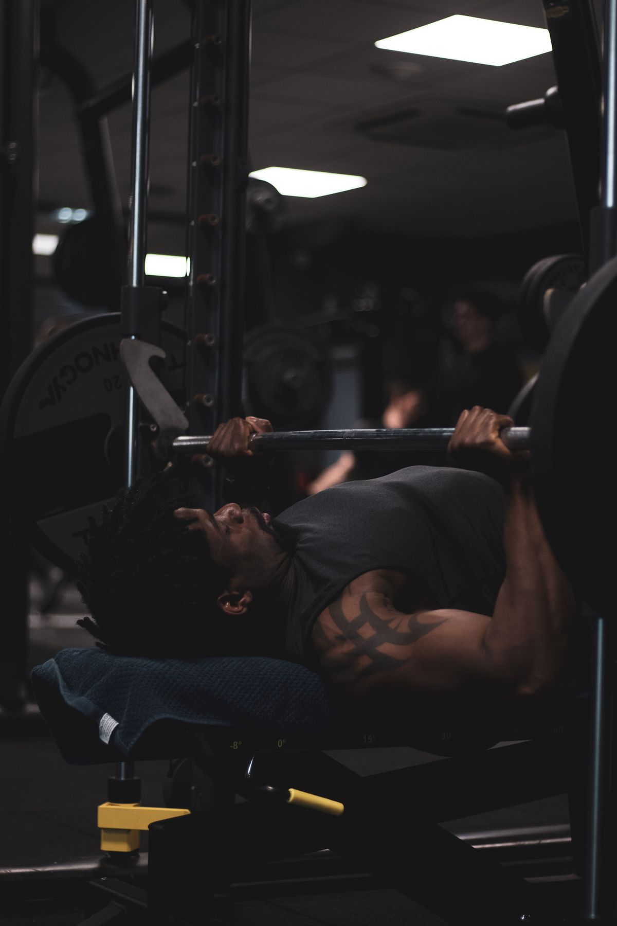 Athlete bench pressing a barbell in a dark strength training gym