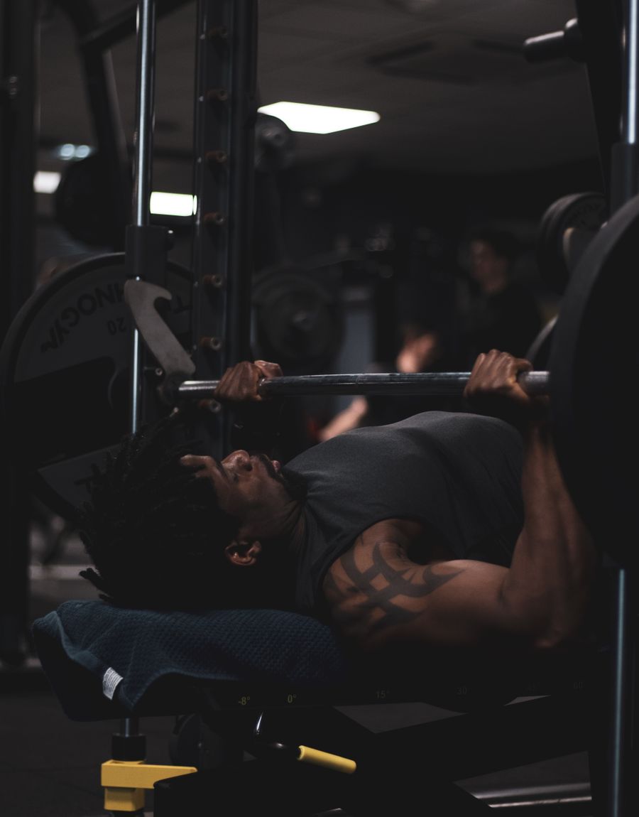 Athlete bench pressing in a dark gym wearing Meridian training wear