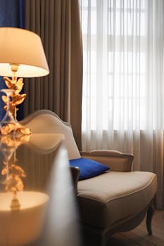 Luxurious room interior featuring a stylish lounge chair and illuminated lamp by the window.