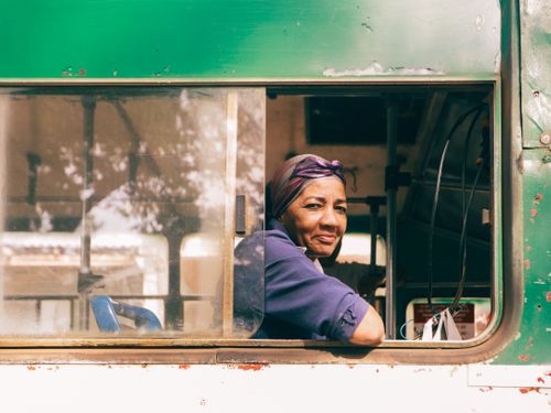 Free A woman sitting on a bus smiling while looking out the window, capturing a candid moment in public transportation. Stock Photo