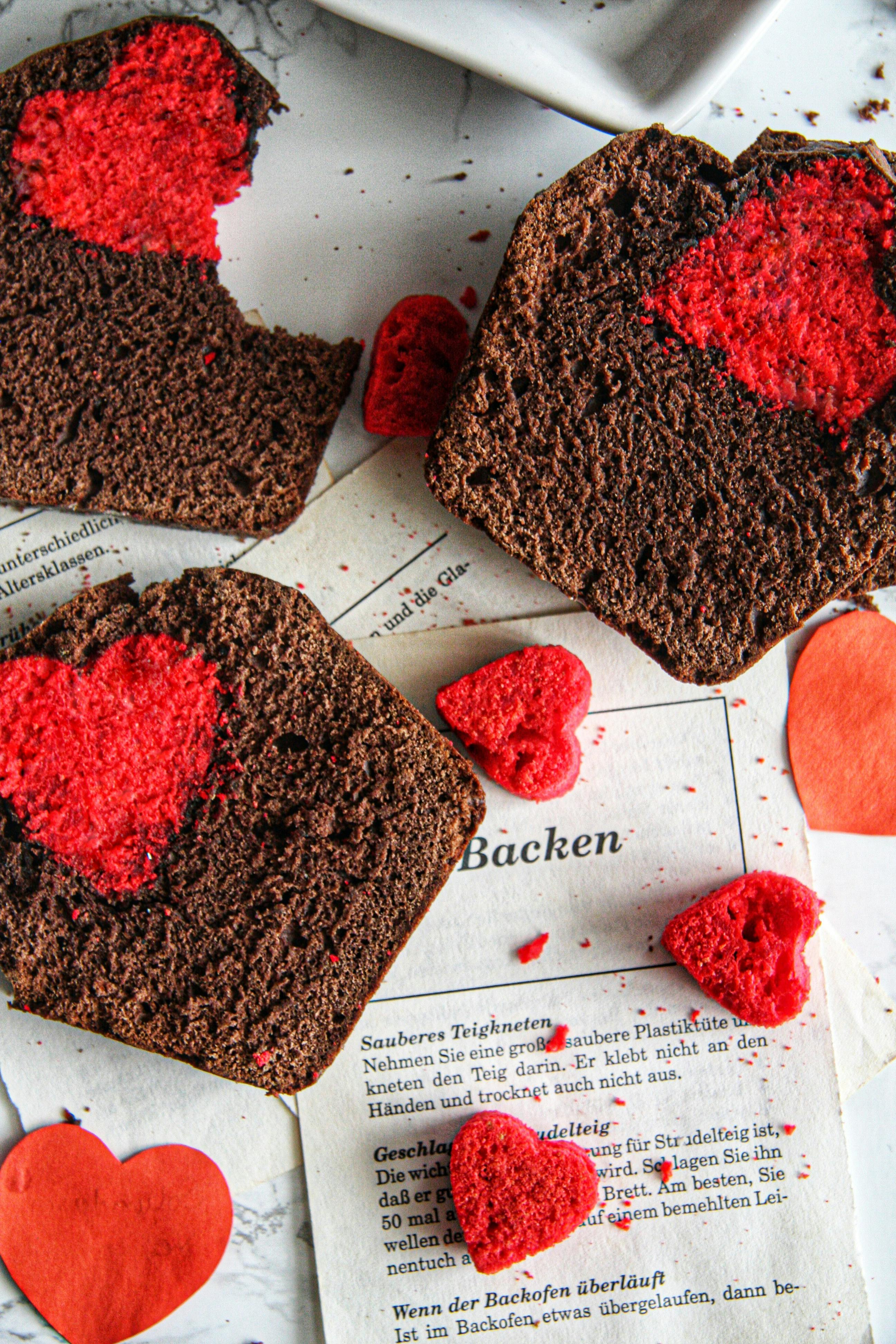 Delicious heart-shaped chocolate cake slices on a background of baking papers, perfect for dessert lovers.