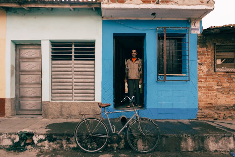 Man Standing Inside A Blue House