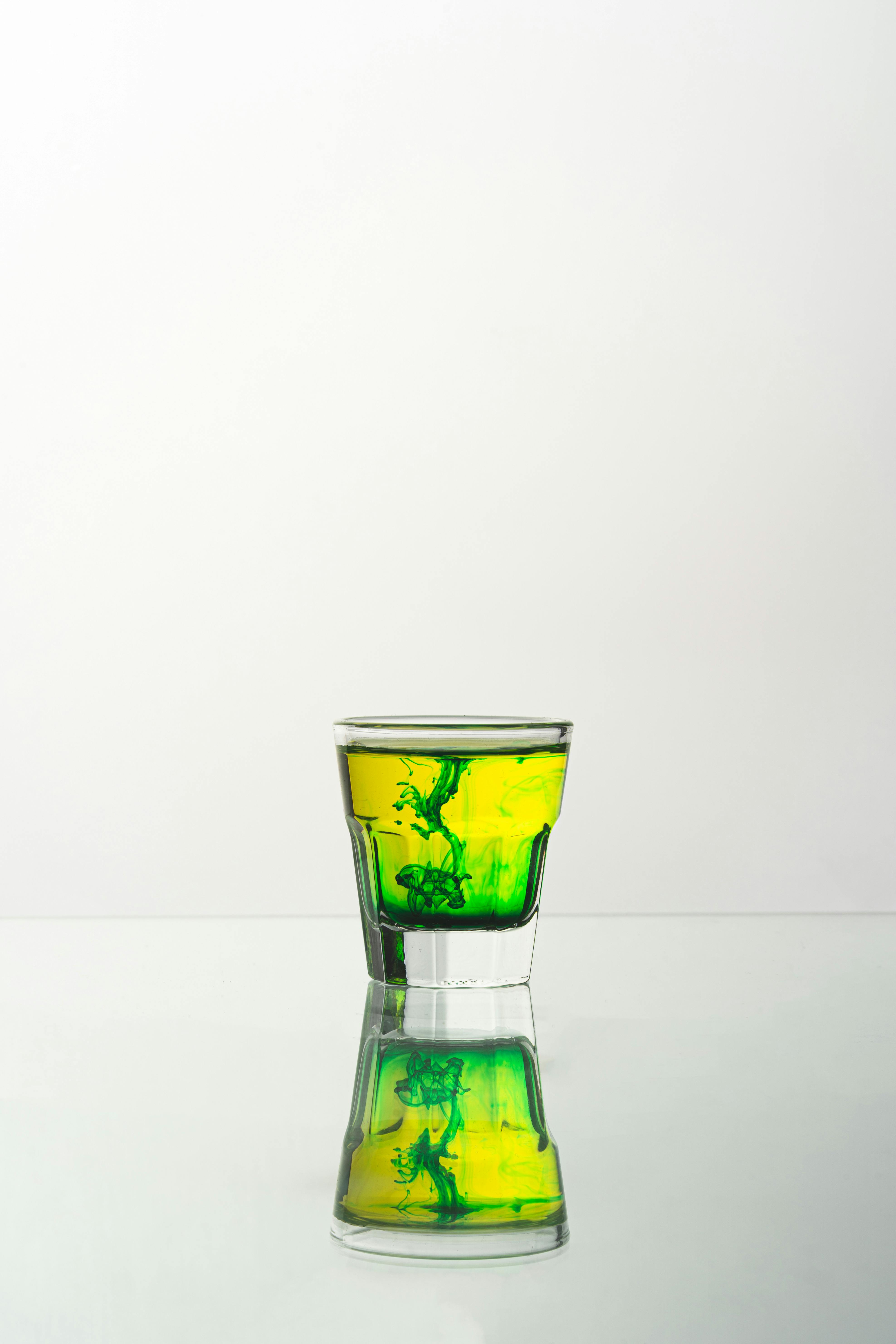 A captivating shot of a vibrant green liquid swirling in a glass, reflecting on a smooth surface.