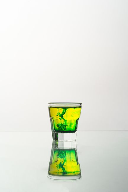 A captivating shot of a vibrant green liquid swirling in a glass, reflecting on a smooth surface.