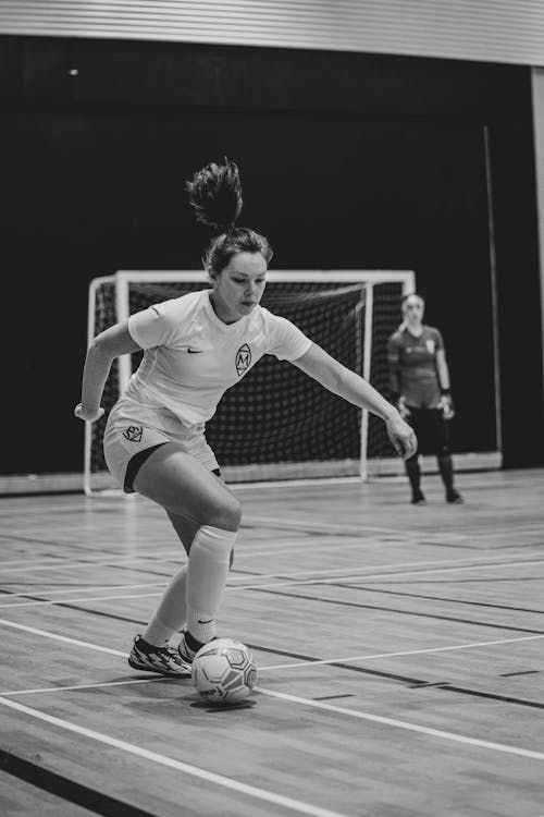 Grayscale Photo of a Woman Playing Soccer