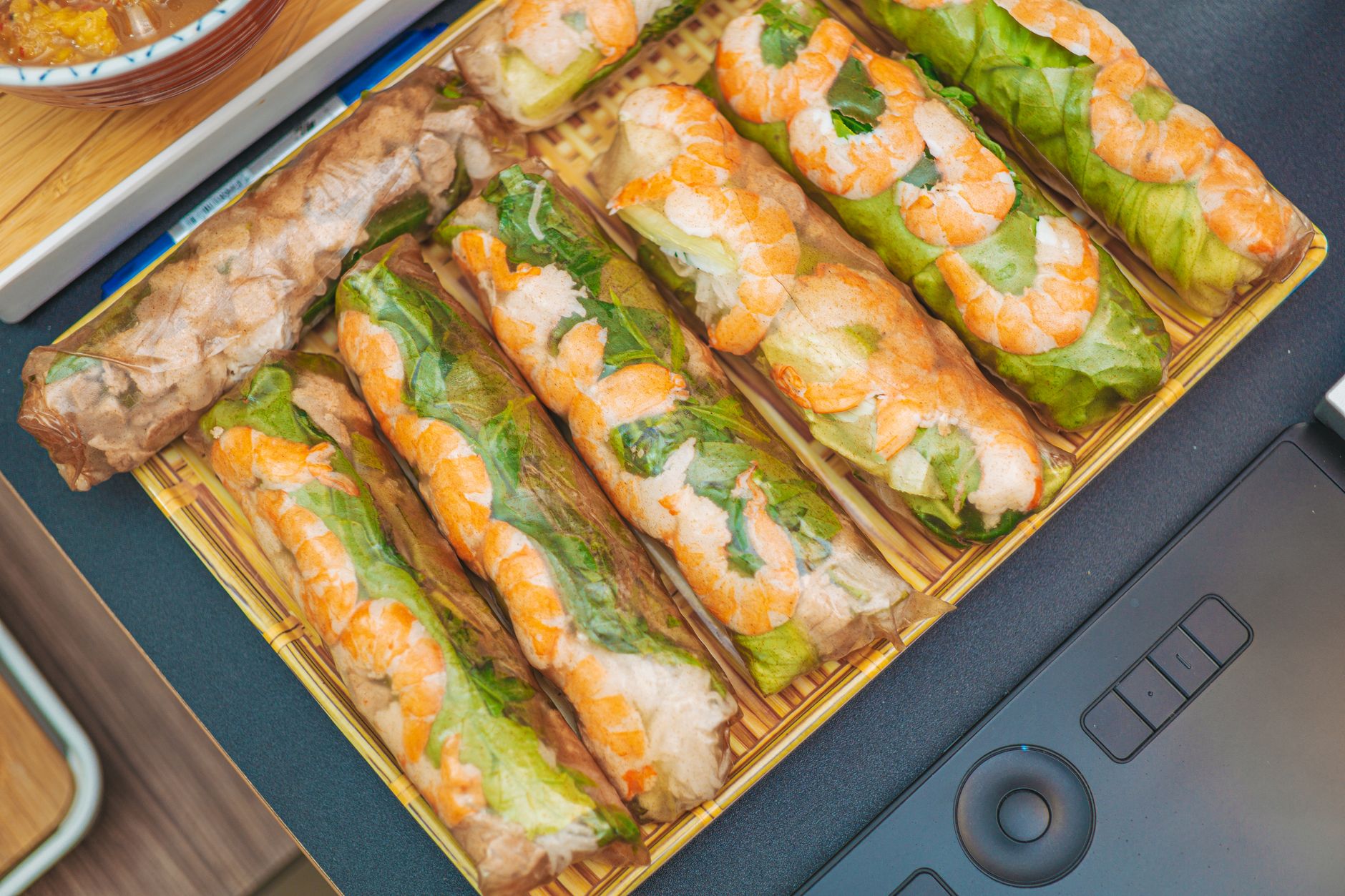 Close-up of fresh Vietnamese spring rolls filled with shrimp, lettuce, and rice noodles on a bamboo tray.