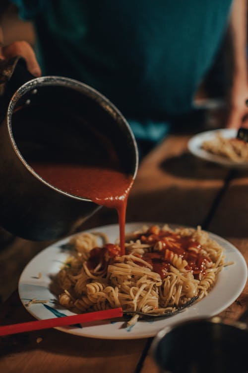 Free Poring Sauce over a Plate of Pasta Stock Photo