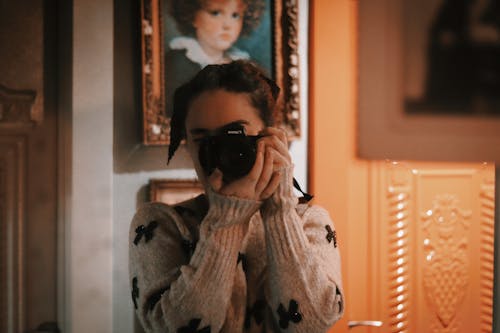 

A Woman in a Gray Sweater Using a Camera