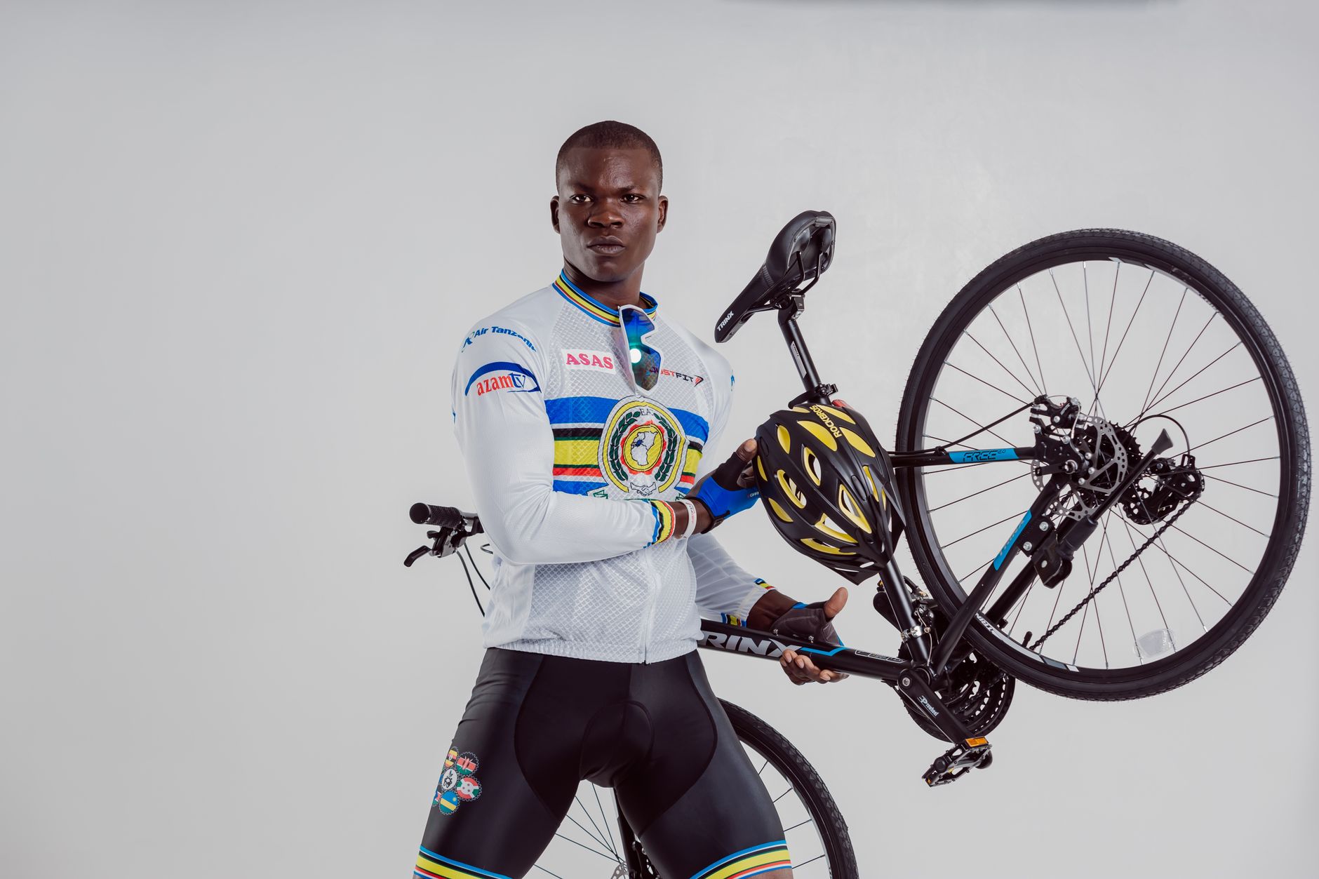 African American cyclist confidently holds a mountain bike indoors, showcasing strength and style.