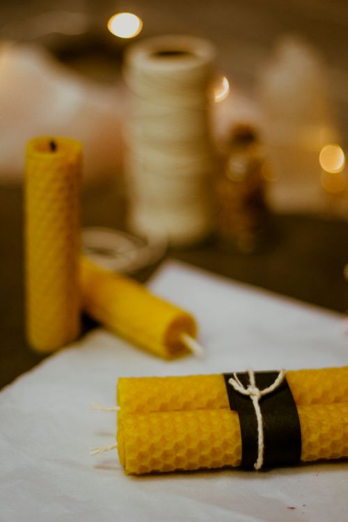 Free Close-up of handmade beeswax candles tied with twine, set against a warm bokeh background. Stock Photo