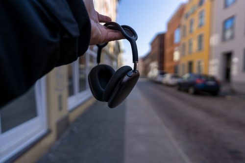 Free Close-up of a hand holding headphones in a city street setting with blurred background. Stock Photo