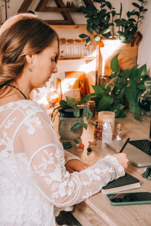 

A Woman in a Blouse Writing on a Notebook