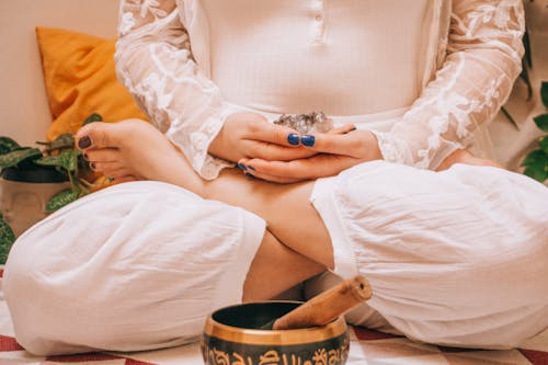 Free A Woman in Lotus Position Holding a Crystal Sitting Near a Metal Bowl Stock Photo