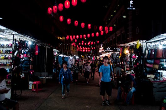 Bustling night market street scene with Asian lanterns in Kuala Lumpur, Malaysia.