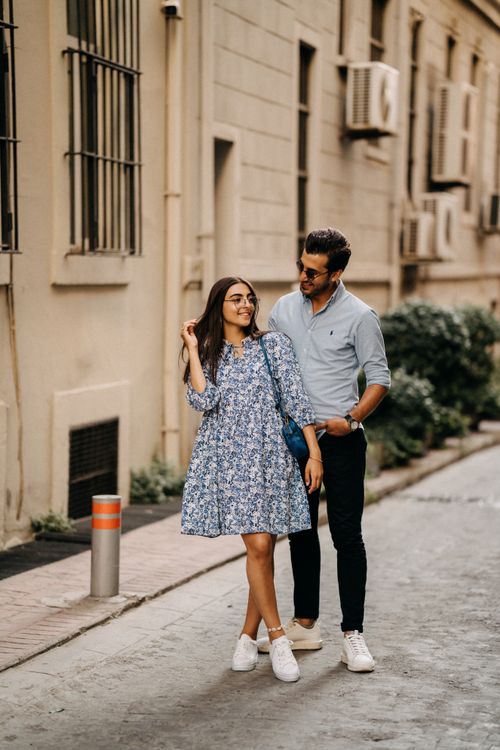 Free A joyful couple walking stylishly on a city sidewalk in summer. Stock Photo
