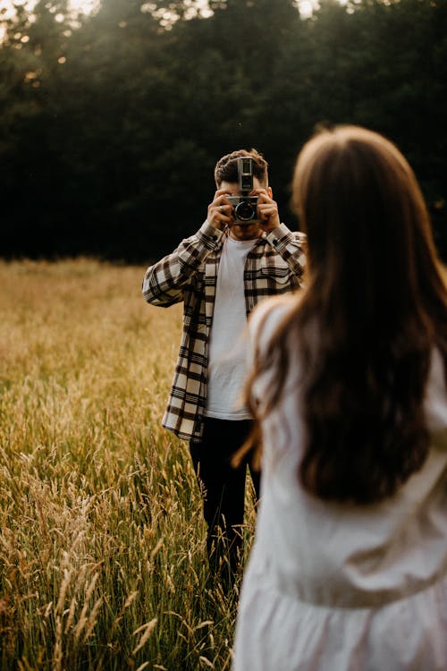 
A Man Taking a Picture of a Woman on a Field