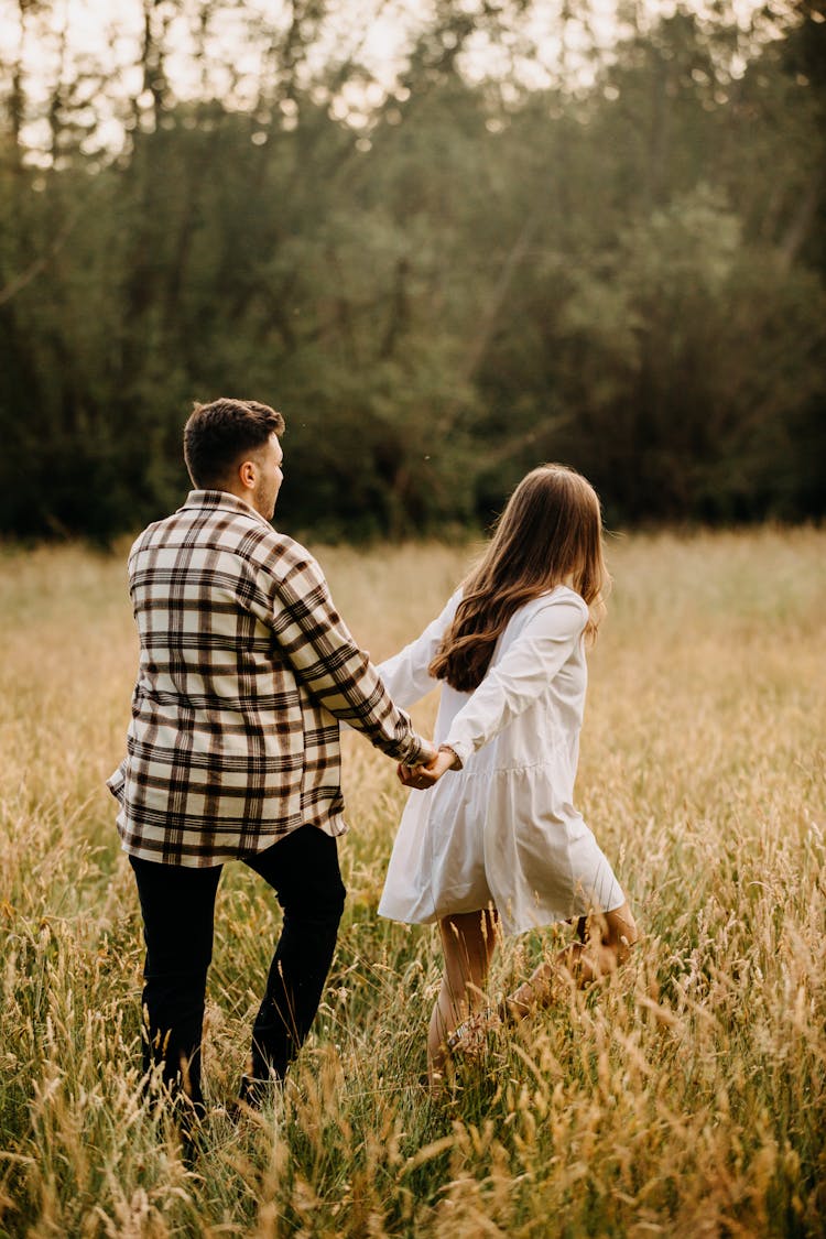 Couple Holding Hands And Running On Field