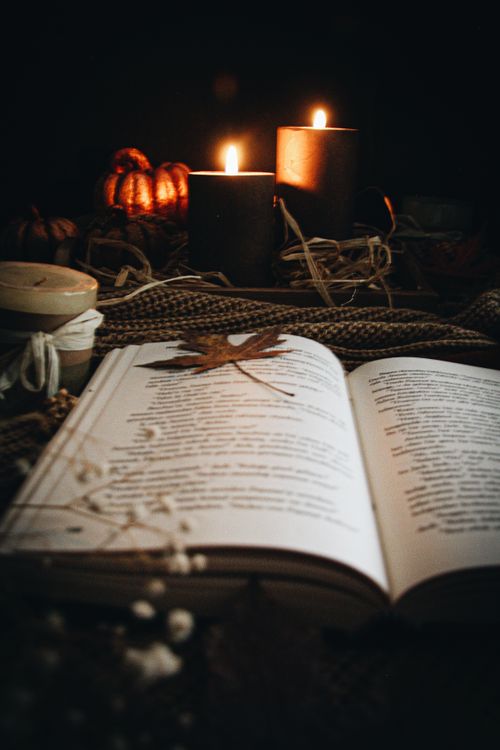 Free An open book with candles and autumn decor creates a warm, cozy evening vibe. Stock Photo