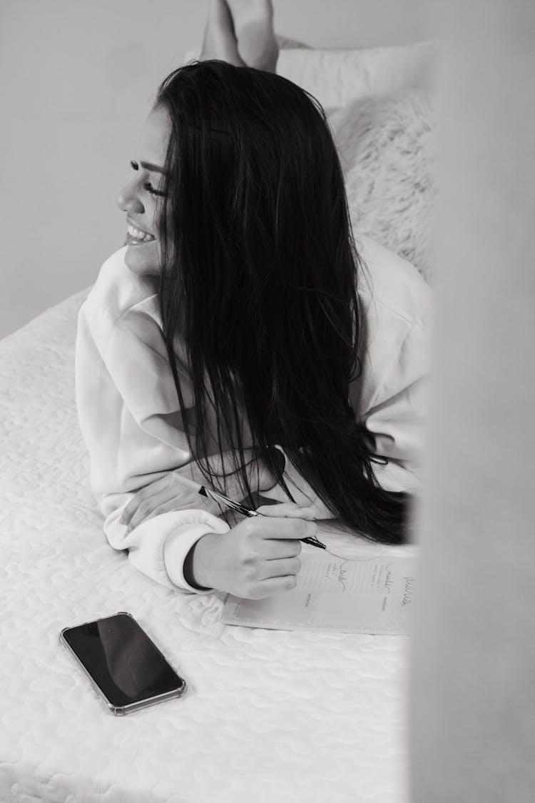 Woman In White Robe Writing On The Bed