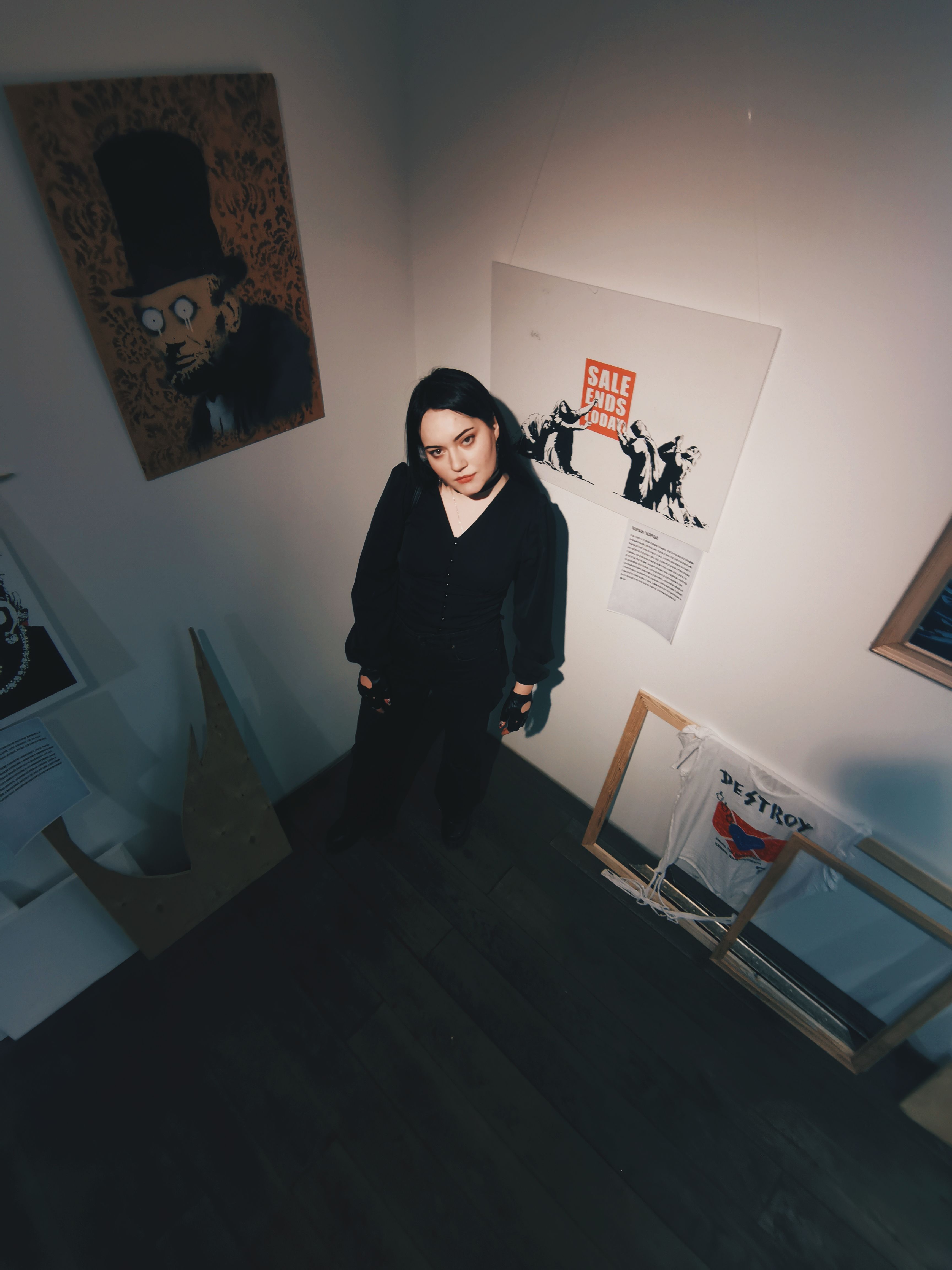 A young woman stands in an art gallery surrounded by modern and eclectic artwork.