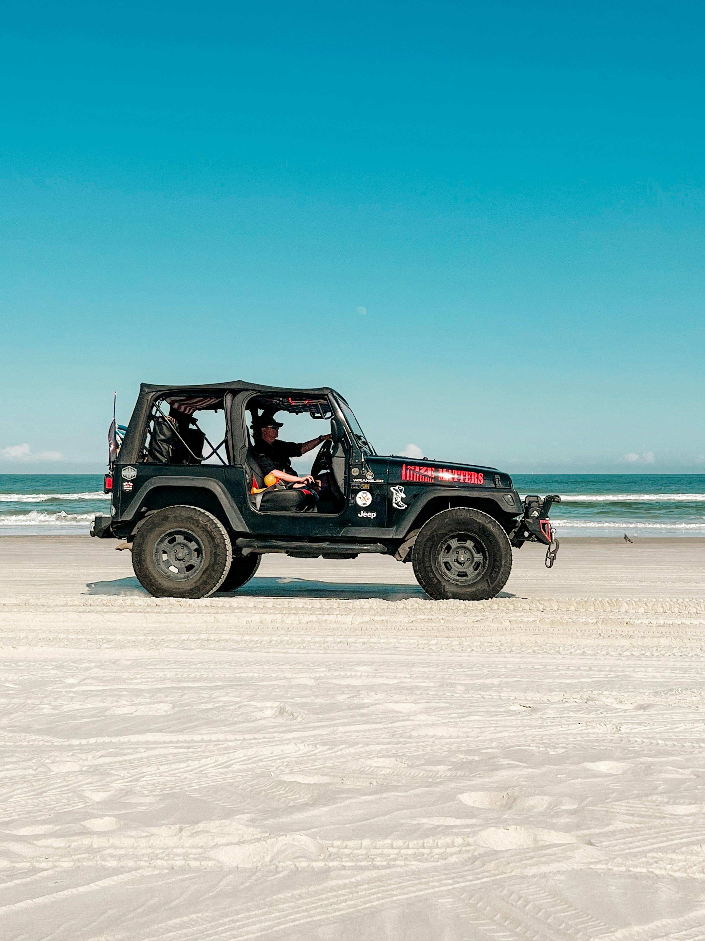 a man driving a jeep at the beach