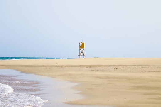 Tranquil beach scene with a solitary lifeguard tower on a sandy shore in Fuerteventura, Canary Islands.